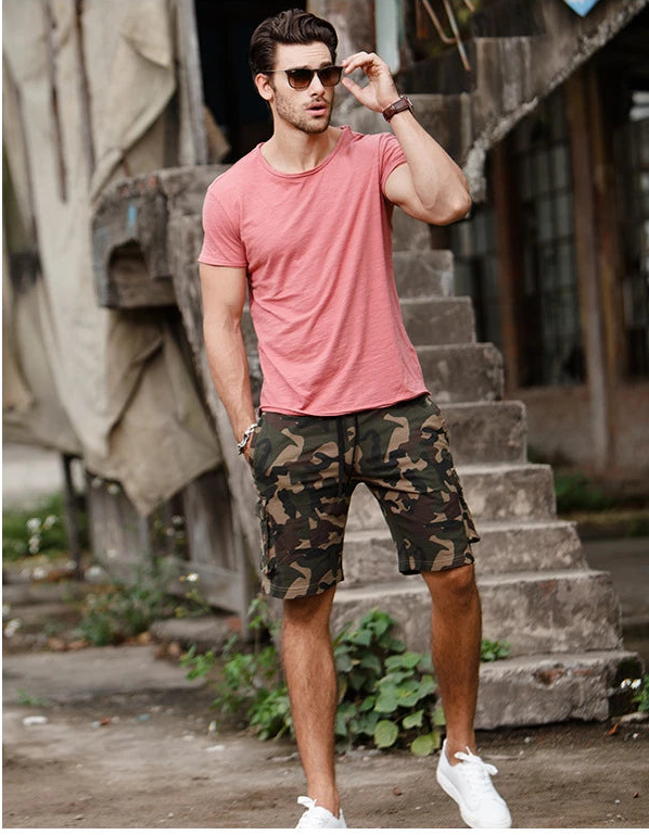 Man wearing men's 100% cotton O-neck t-shirt in pink with short sleeves, styled with camouflage shorts, lifestyle outfit front view