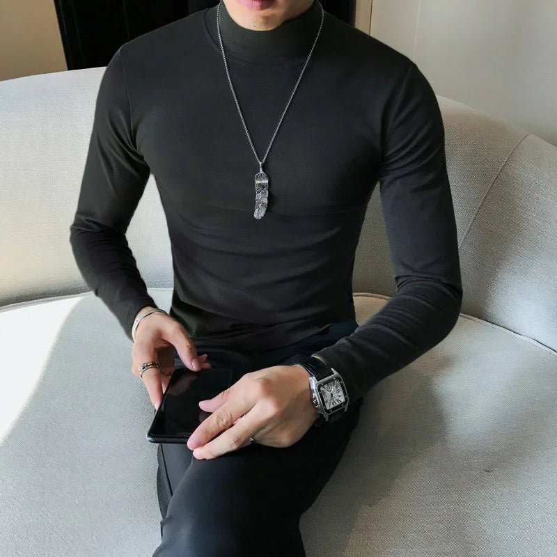 Men's turtleneck long sleeve shirt in black - slim fit high elastic cotton pullover, front view styled on model seated with dark pants