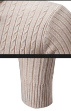 Close-up detail of beige cable knit turtleneck sweater showing shoulder and hem texture