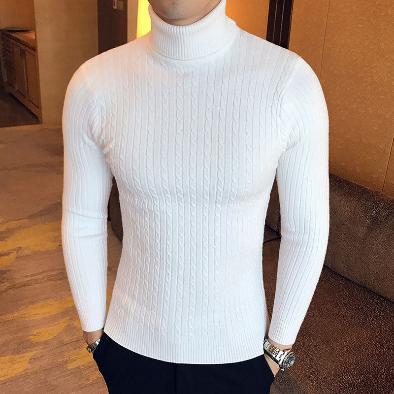 Man wearing white turtleneck cable knit pullover sweater with navy pants, lifestyle front view