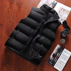 Men's black waterproof insulated vest flat lay on wooden surface with watch and magazine accessories