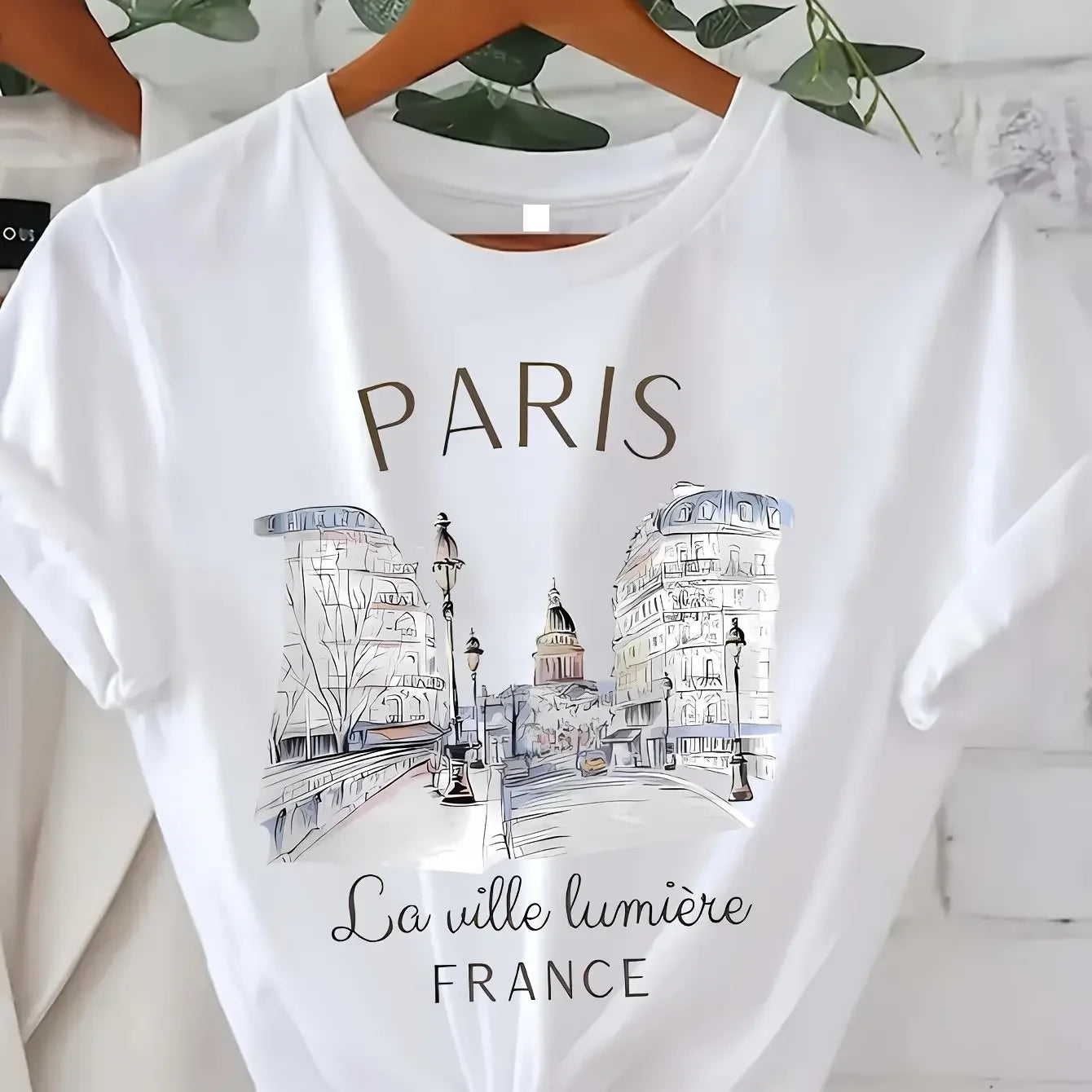 Women's white Paris graphic tee with La Ville Lumiere France skyline print on hanger, vintage 90s style crew neck