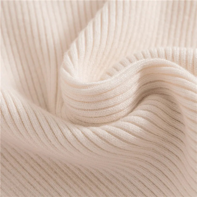 Close-up detail of beige cashmere blend ribbed knit turtleneck sweater showing soft fabric texture