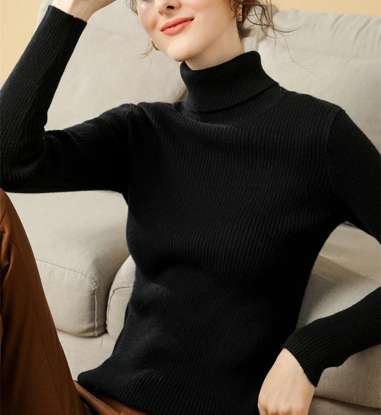 Woman wearing black cashmere blend ribbed turtleneck sweater with hand raised, lifestyle front view