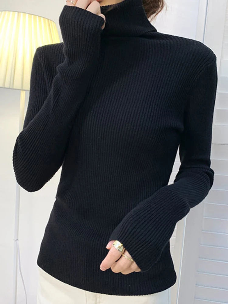 Woman wearing black cashmere blend ribbed turtleneck sweater with turtleneck pulled up over chin, front view