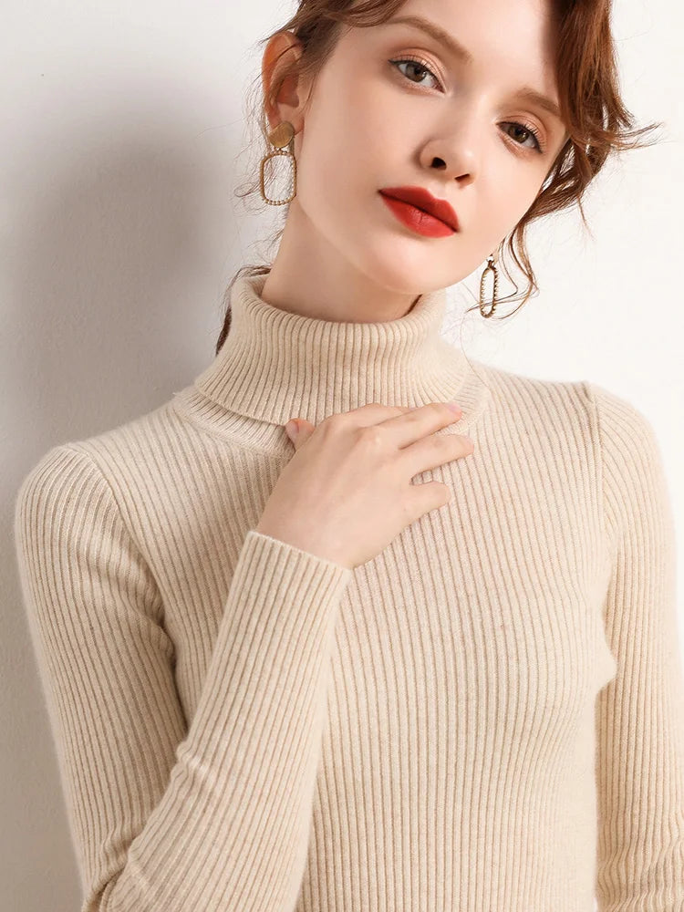 Woman wearing cream ivory cashmere blend ribbed turtleneck sweater with gold earrings, hand at collar, front view