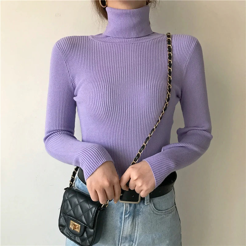 Woman wearing lavender cashmere blend ribbed turtleneck sweater with jeans and black quilted chain bag, front view