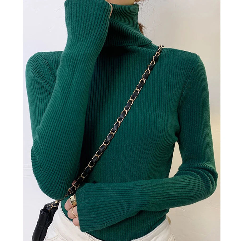 Woman wearing teal green cashmere blend ribbed turtleneck sweater with black chain bag, front view