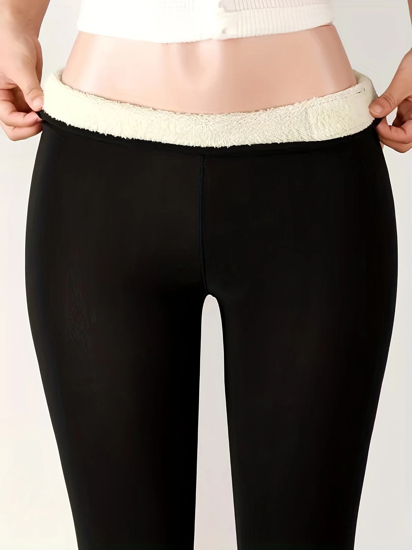Women's high waist fleece lined thermal leggings in black, close-up of waistband folded down showing thick cream fleece interior lining