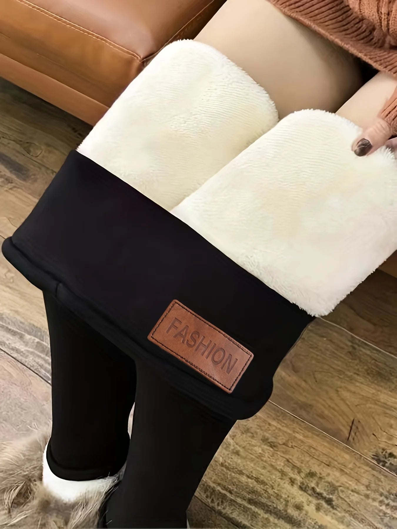 Women's high waist fleece lined thermal leggings in black, side view with cream fleece interior folded down showing thick lining and leather patch detail