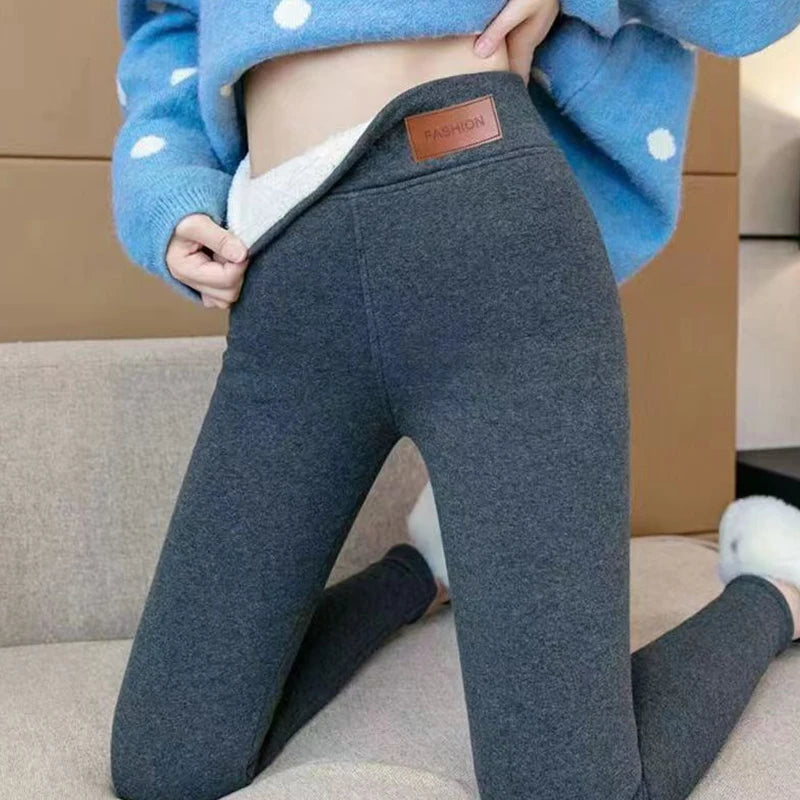 Women's high waist fleece lined thermal leggings in dark gray, close-up of high waist fit and leather patch detail styled on model