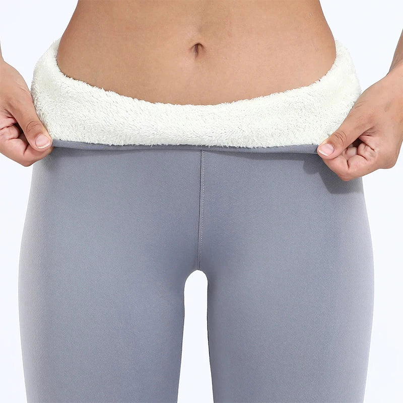 Women's high waist fleece lined thermal leggings in light gray, close-up of waistband folded down showing thick cream fleece interior lining, held by model