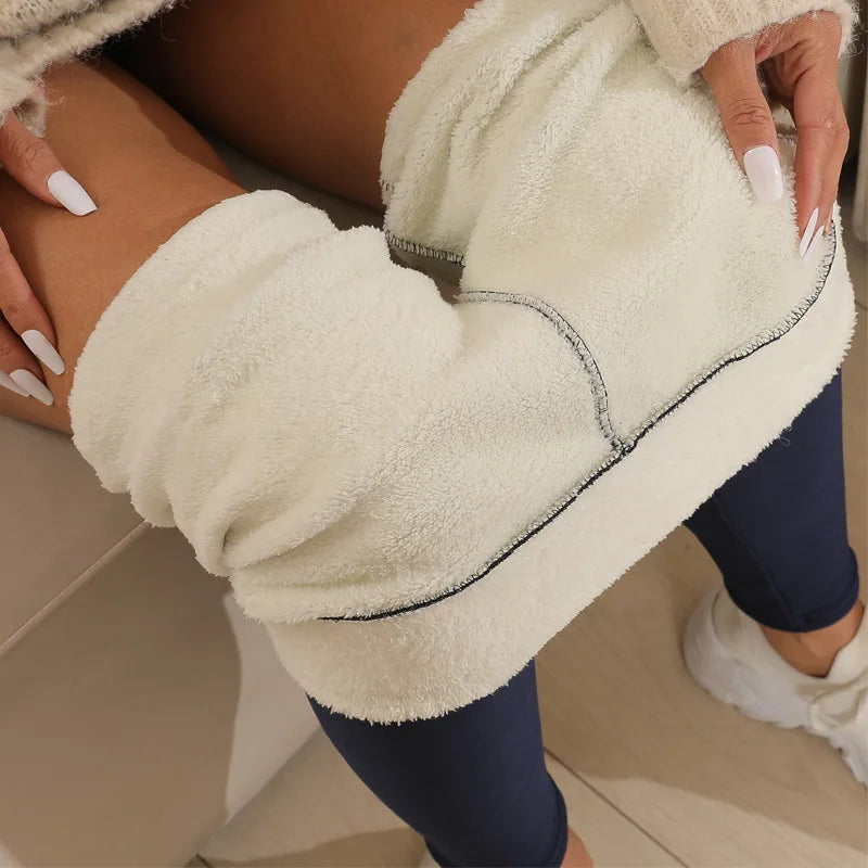 Women's high waist fleece lined thermal leggings in navy blue, close-up of thick plush cream fleece waistband folded down, held by model