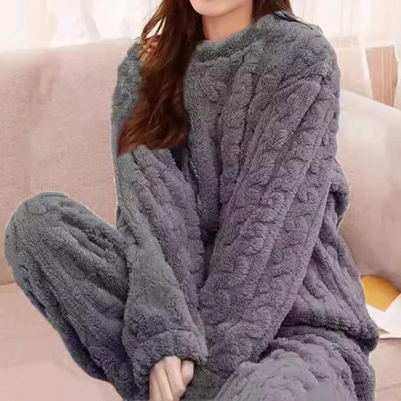 Women's fleece pajama set in gray with textured dot pattern - long sleeve top and elastic waist pants, styled on model seated on sofa, front view