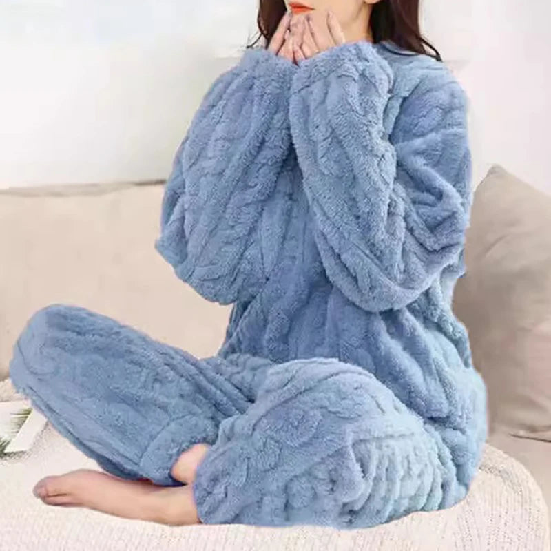 Women's fleece pajama set in light blue with textured ruffle detail - long sleeve top and elastic waist pants, styled on model seated on bed, front view