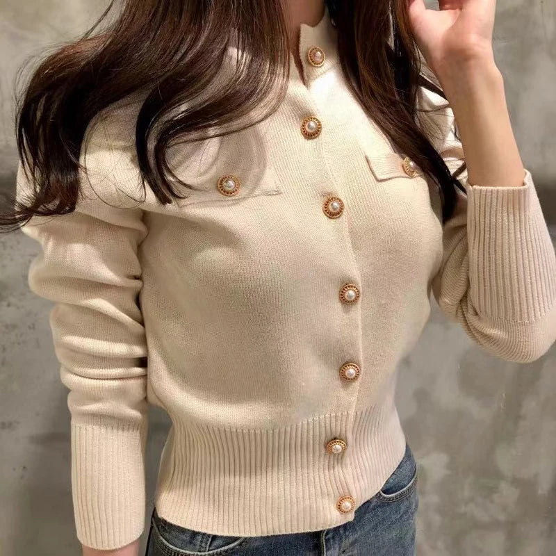 Women's knitted cardigan in cream - close-up of decorative gold buttons, chest pocket and ribbed cuffs, front view