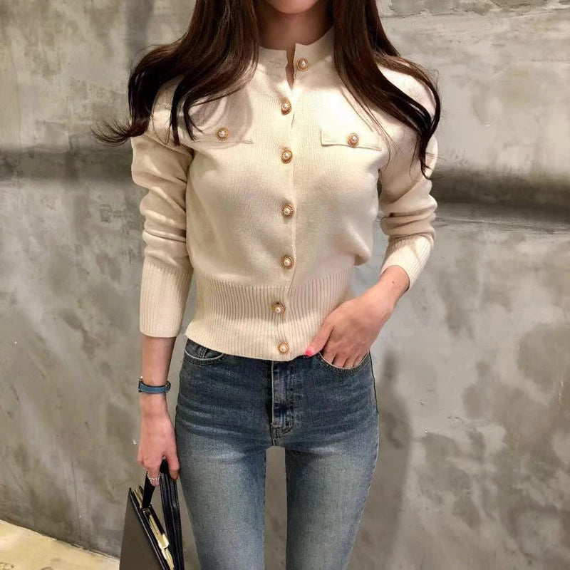 Women's knitted cardigan in cream with gold button closure - long sleeve button-front sweater coat, full length front view styled with jeans