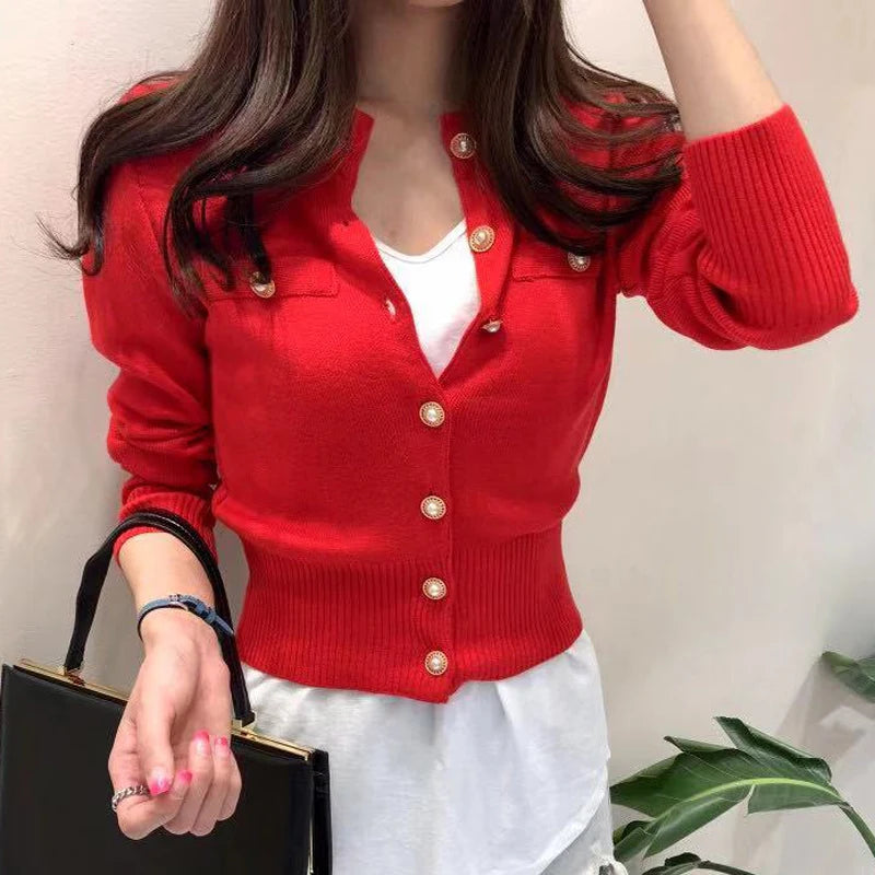 Women's knitted cardigan in red - close-up of gold pearl button closure and ribbed cuffs, front view