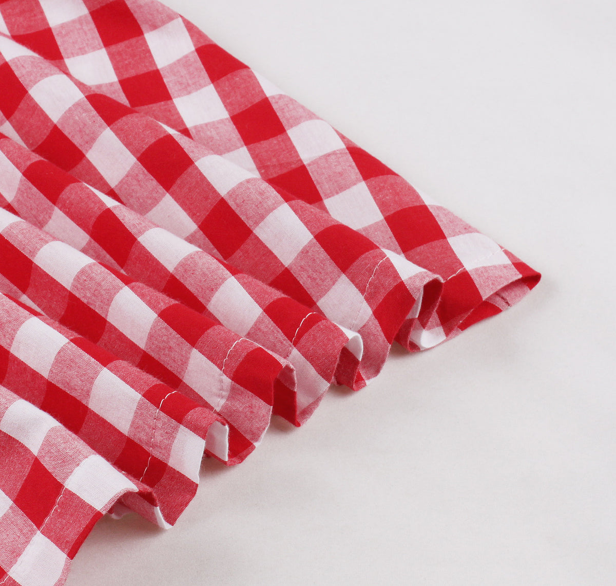 Close-up of ruffled hem on red and white plaid A-line midi dress