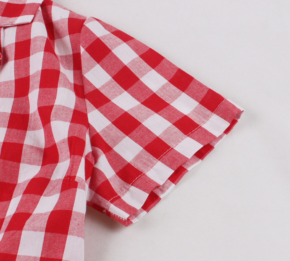 Close-up of short sleeve on red and white plaid A-line dress showing fabric texture