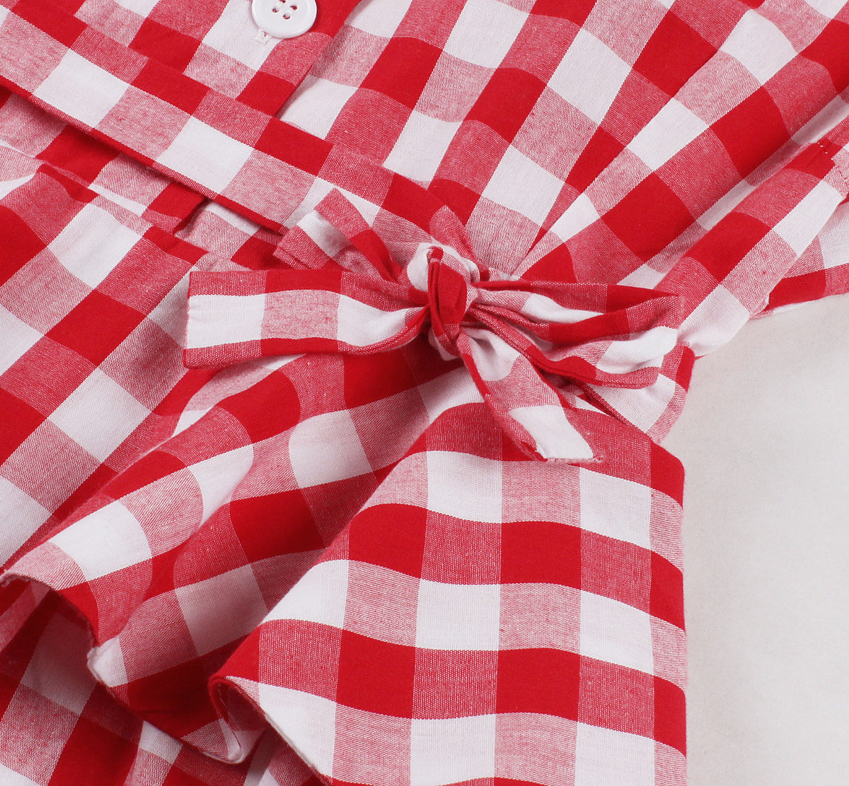 Close-up of red and white plaid dress tie bow knot at waist with ruffled detail