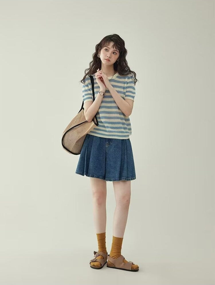 Women's wide leg pleated denim culottes in blue, full body front view styled on model with shoulder bag