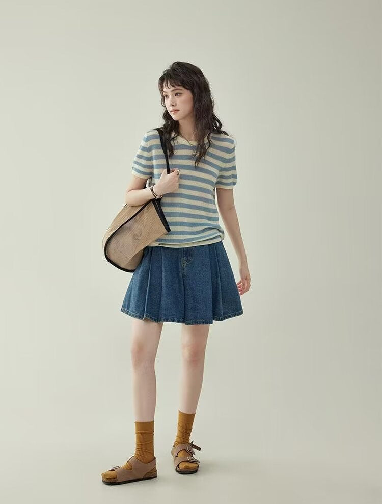Women's wide leg pleated denim culottes in blue, full body side view styled on model with shoulder bag