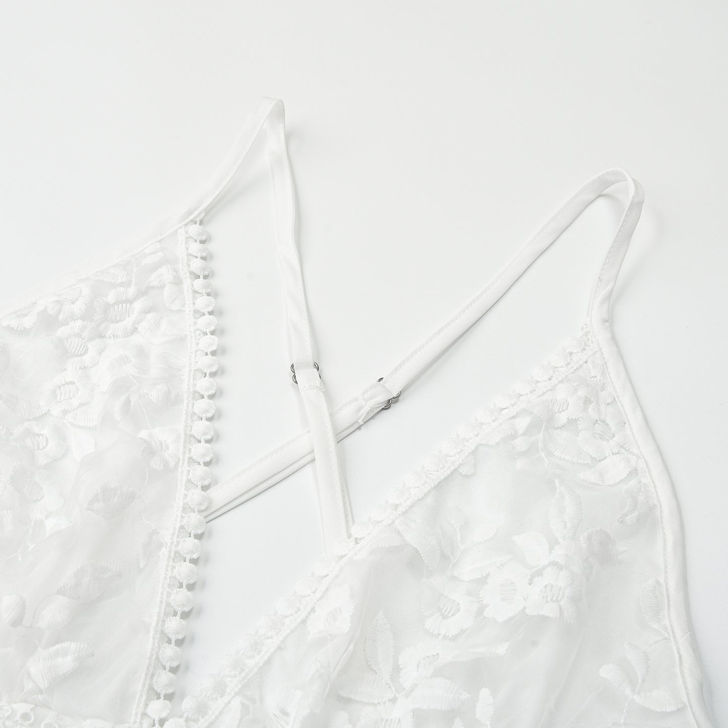 Closeup detail of white lace beach dress cross-back straps and lace fabric texture