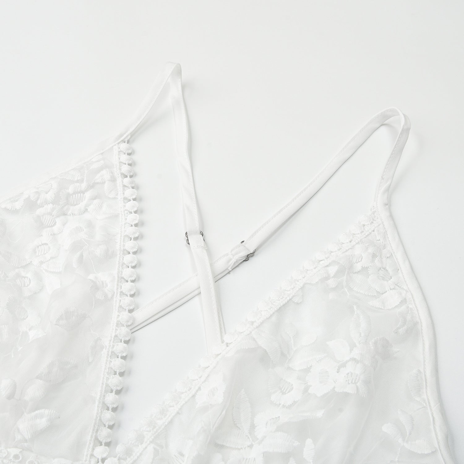 Closeup detail of white lace beach dress cross-back straps and lace fabric texture