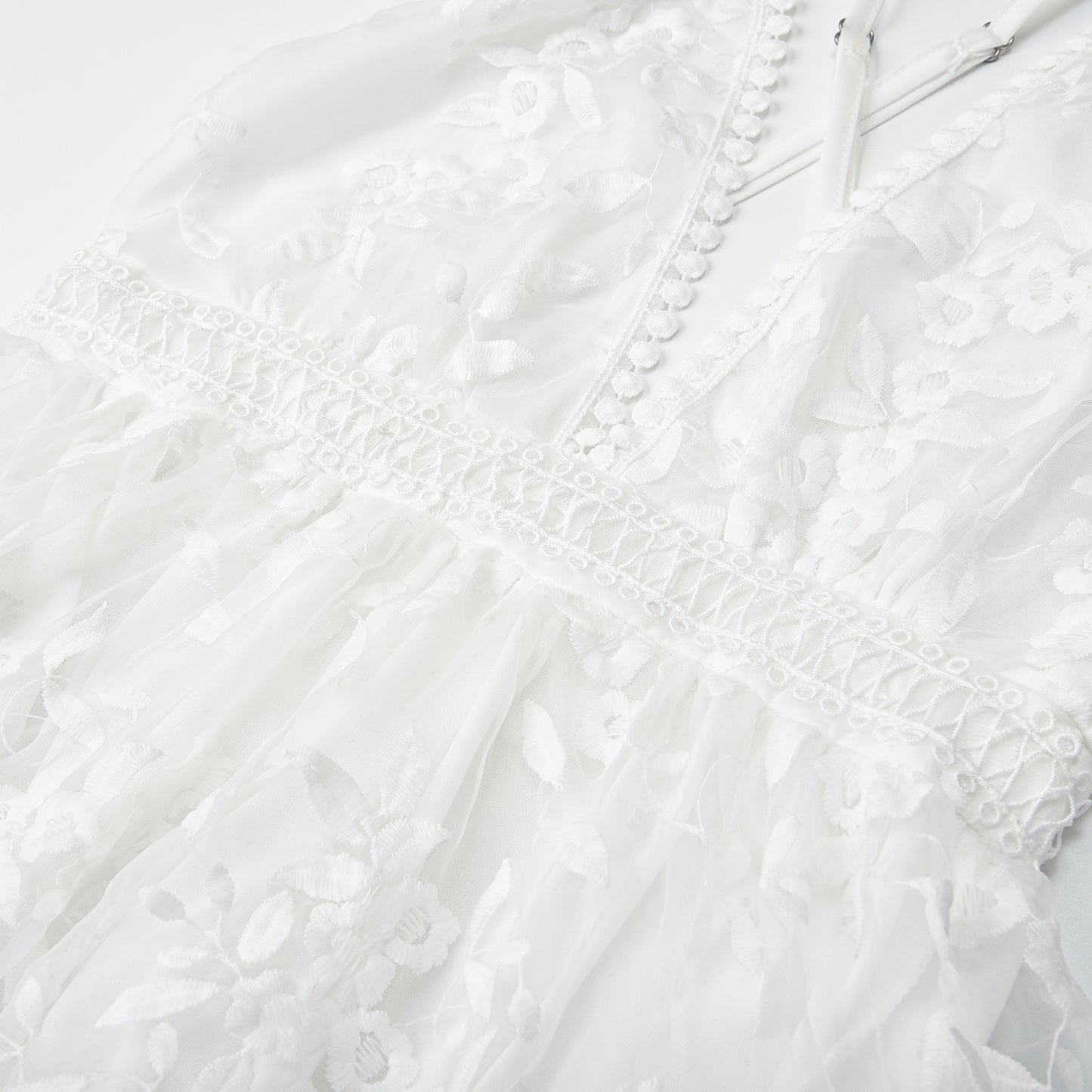 Closeup detail of white lace fabric texture and floral embroidery pattern on beach dress
