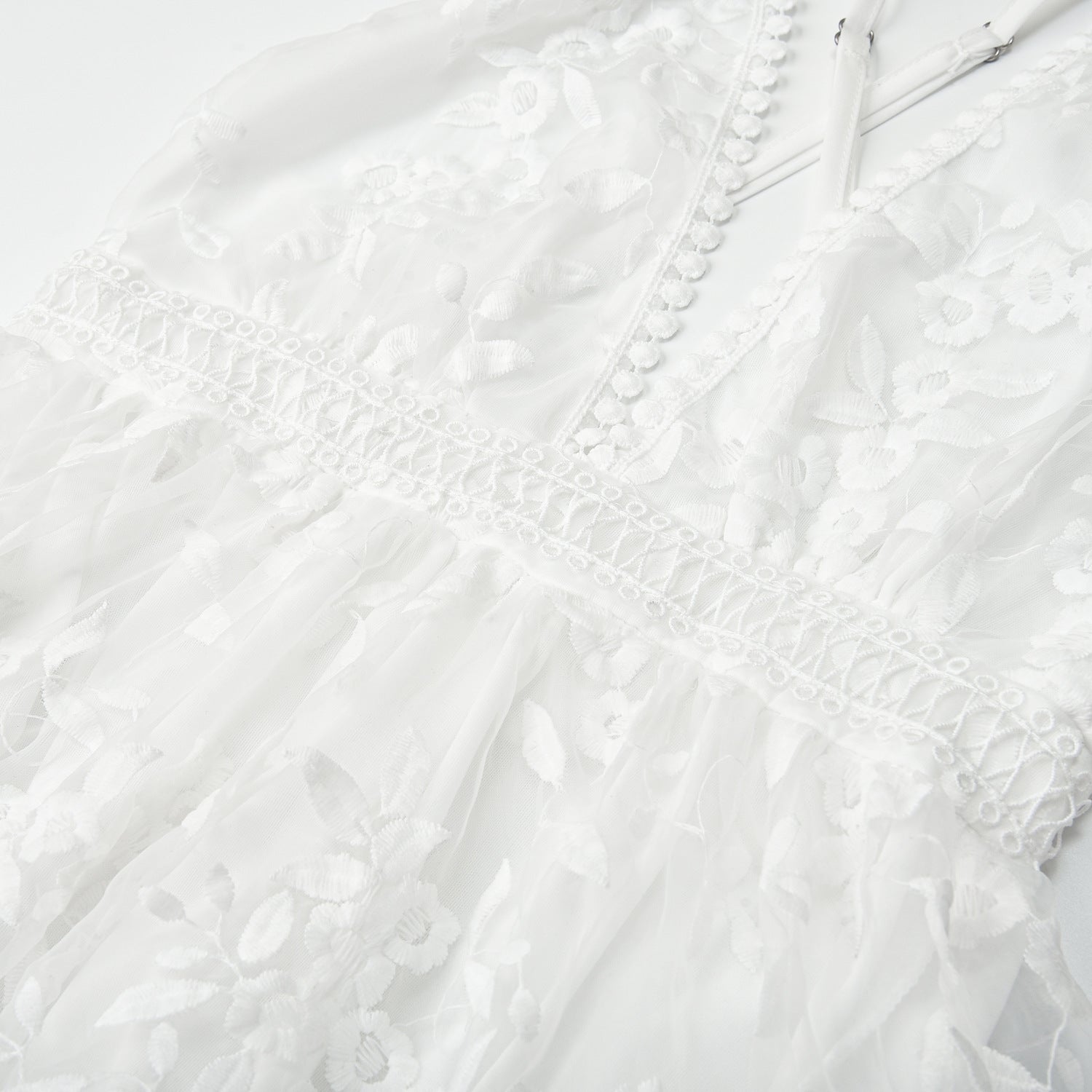 Closeup detail of white lace fabric texture and floral embroidery pattern on beach dress