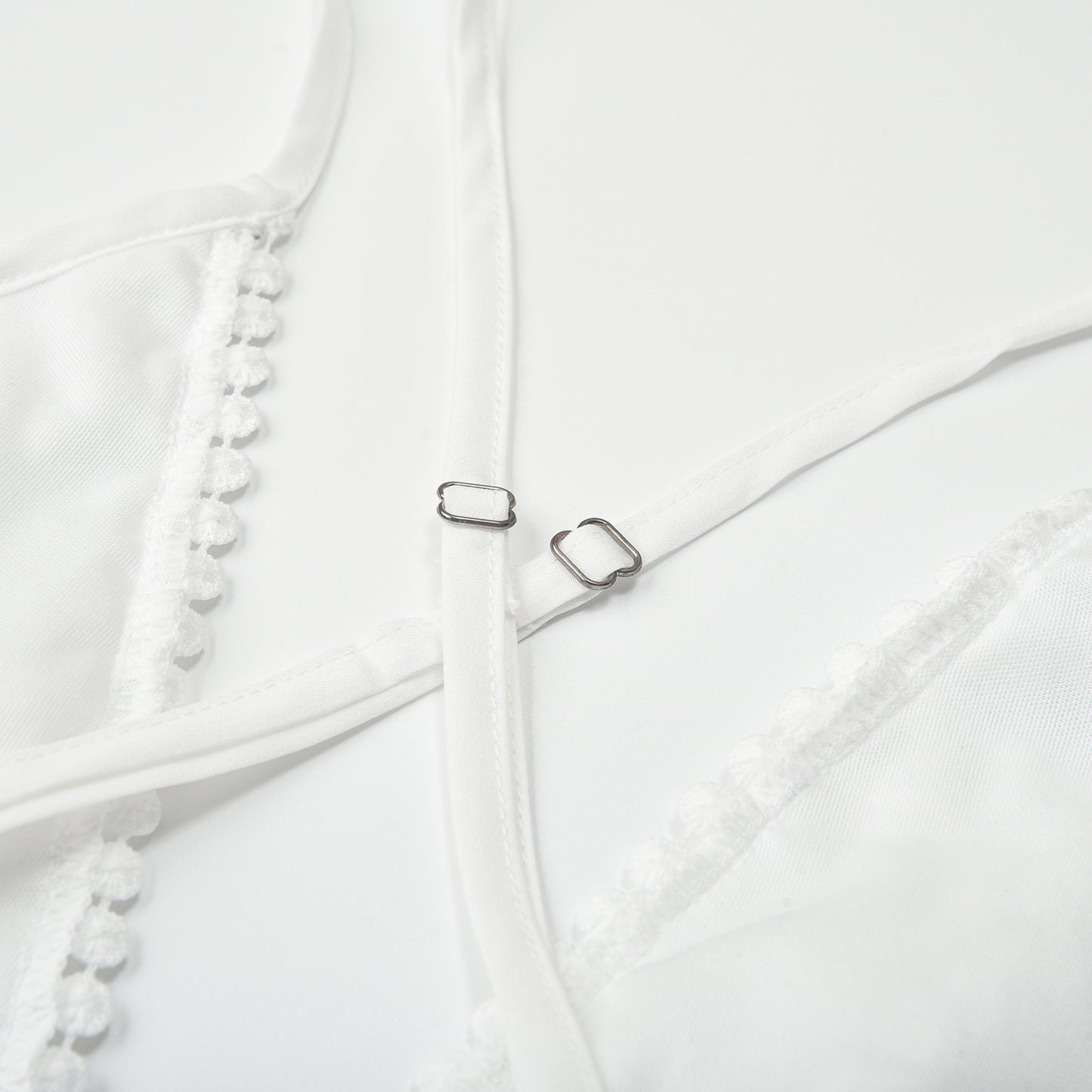 Closeup detail of white lace beach dress metal ring buckle strap hardware and fabric texture