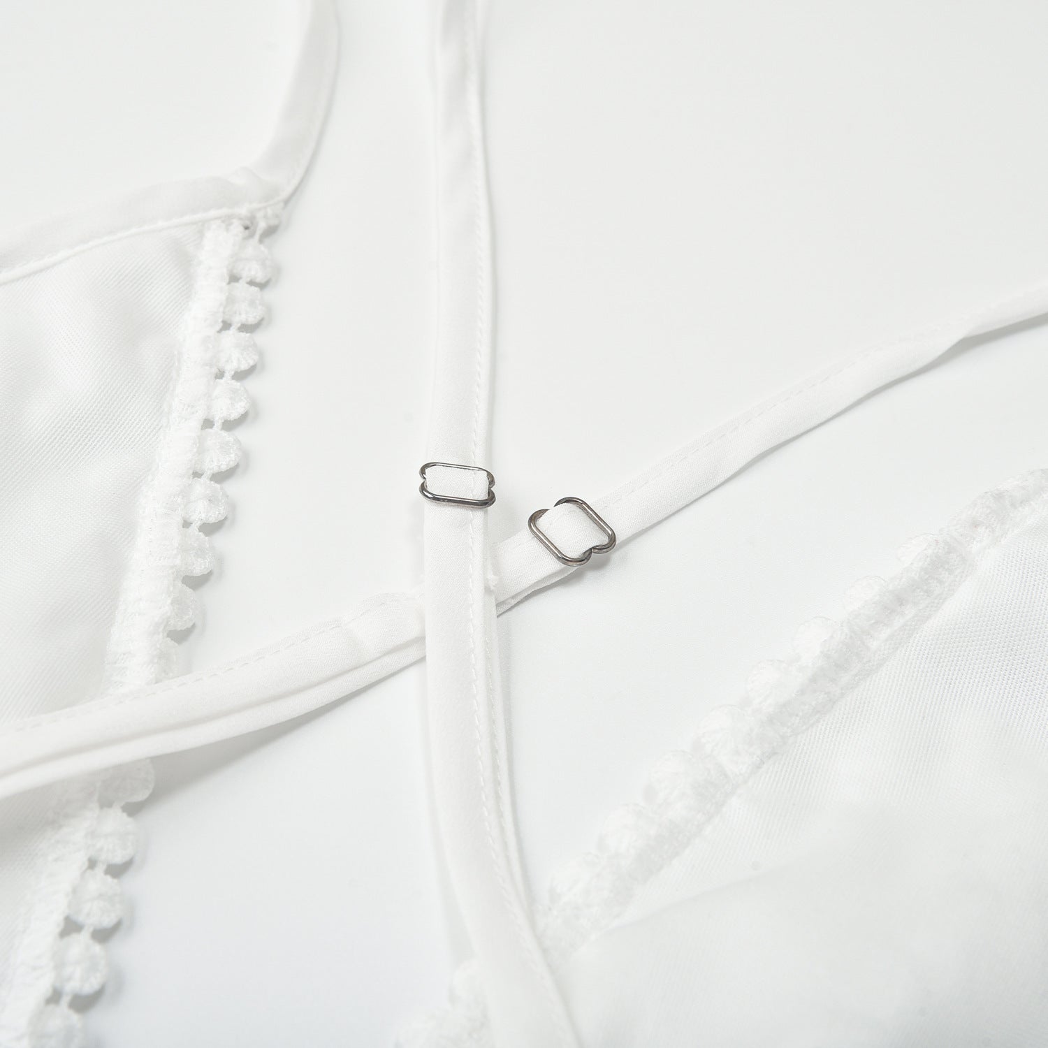 Closeup detail of white lace beach dress metal ring buckle strap hardware and fabric texture