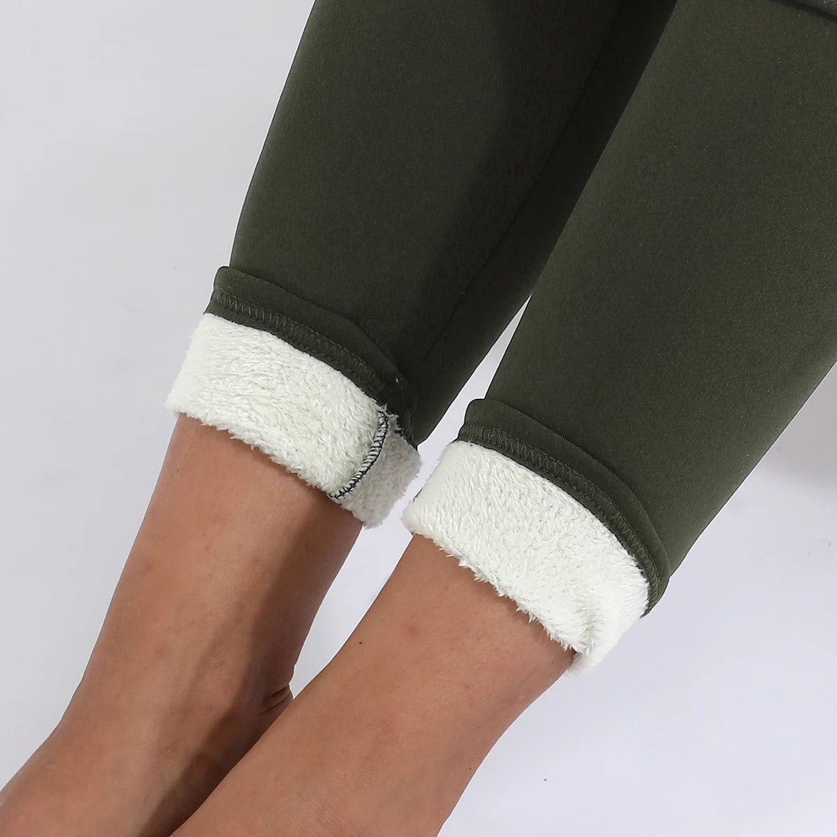 Women's high waist velvet winter leggings in olive green, close-up of ankle area showing cream fleece cuff rolled up with stitching detail