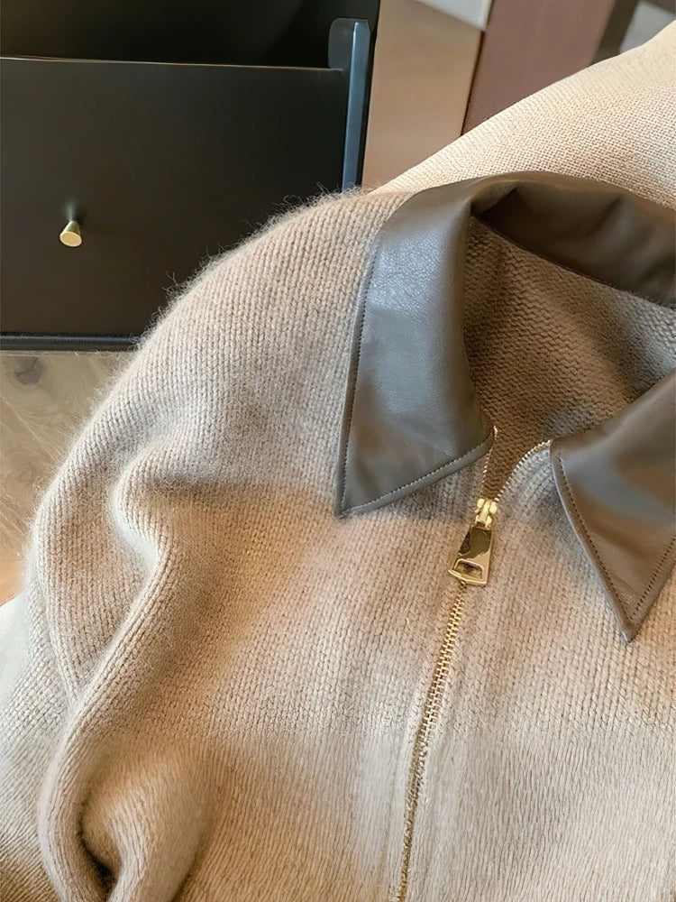 Nahaufnahme des braunen Kunstlederkragens und des goldfarbenen Reißverschlusses an der kurzen grauen Strickjacke